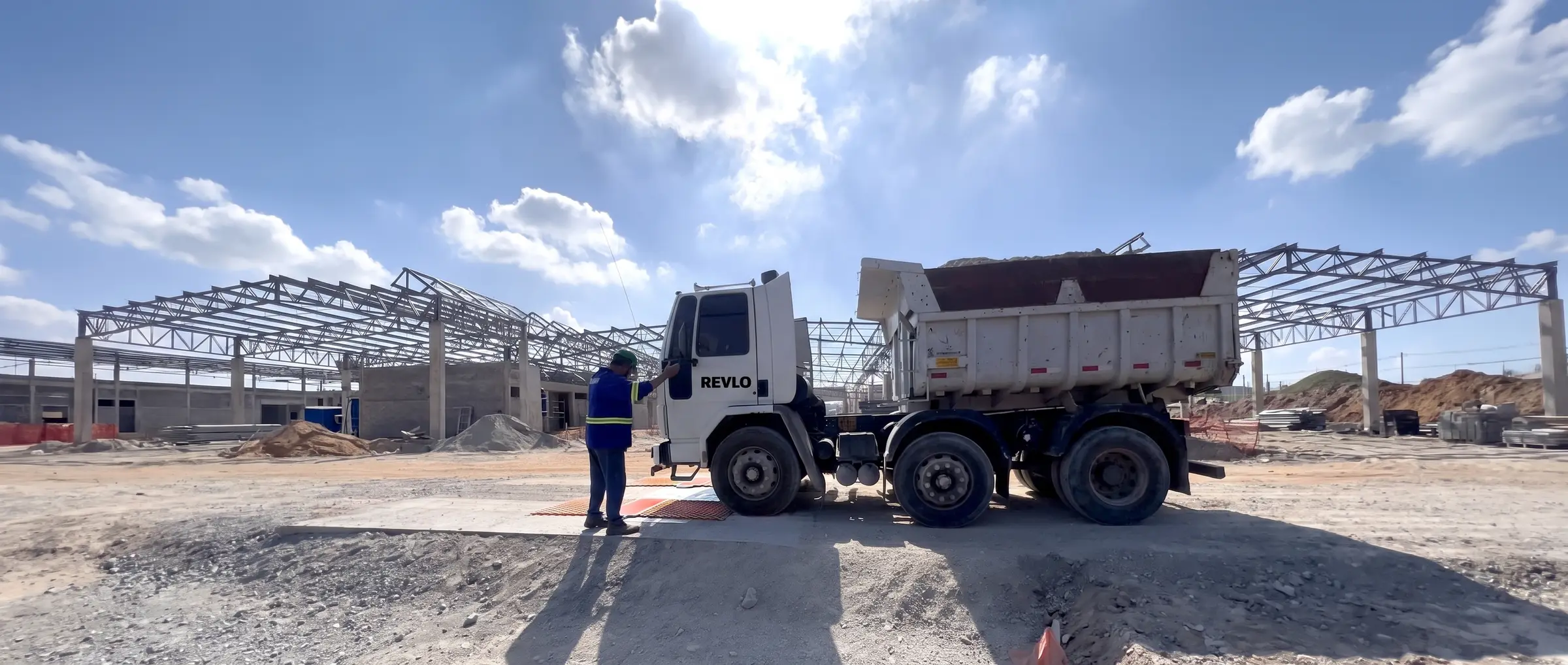 Caminhão basculante sobre as plataformas da balança rodoviária móvel Revlo num canteiro de obra